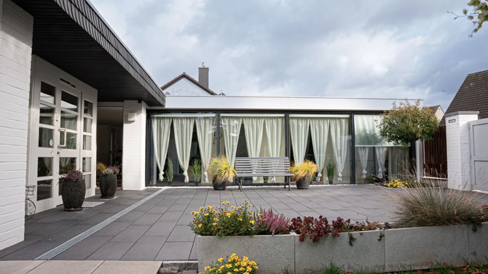 Gepflegte Terrasse mit Überdachung und Bepflanzung an einem Wohnhaus